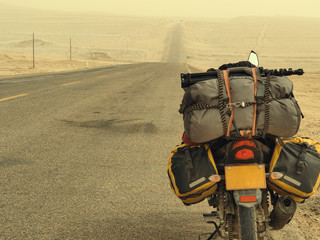 Motorcycle with travel baggage parked by the roadside in sandstorm weather