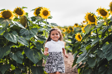 Pretty girl standing among sunflowers