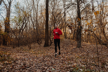 Fototapeta premium A guy in a red windbreaker runs in the autumn forest.