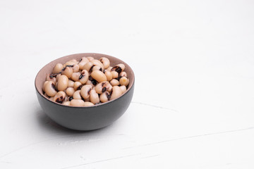 Cooked Fradinho beans in a black clay pot, isolated on a white background.