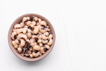 Cooked Fradinho beans in a black clay pot, isolated on a white background.