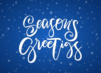 Handwritten modern brush type lettering of Season's Greetings on blue snowflakes background.