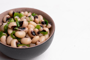 Cooked Fradinho beans in a black clay pot, isolated on a white background.