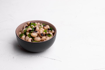 Cooked Fradinho beans in a black clay pot, isolated on a white background.