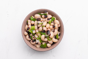 Cooked Fradinho beans in a black clay pot, isolated on a white background.