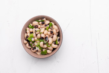 Cooked Fradinho beans in a black clay pot, isolated on a white background.