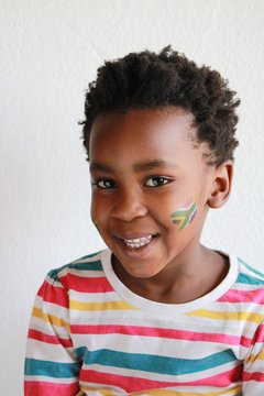 young african child with afro and face paint of the south african flag