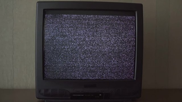 outdated small black and white TV with flashing screen located on table in apartment extreme close view