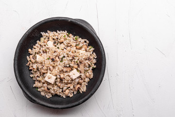 Baião de Dois - Brazilian Traditional Food - made with sausage, curd cheese, dried beef and rice in a black clay pot, on white background. Typical dish of Northeast Brazil.