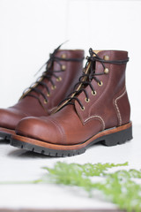 ฺBrown leather shoes with vintage camera on a wooden floor.Brown vintage leather boots aligned selective focus.Men leather shoes 