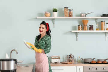 Portrait of beautiful pin-up woman washing dishes in kitchen