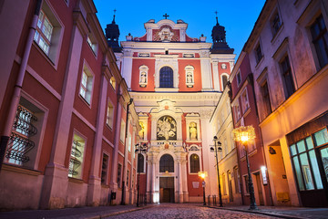 The  facade of the baroque church and the cobbled street at night in Poznan.