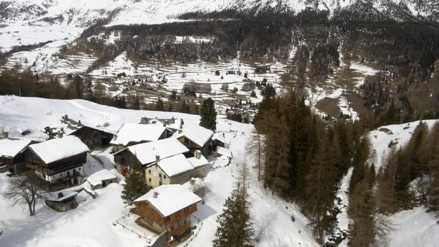 aerial over snowy log house lodge village in sunny winter day
