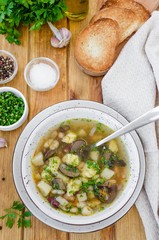 Soup with beans, mushrooms and dumplings in a bowl on a dark wooden background with herbs and garlic. Vegan (lean) dish. Rustic style.