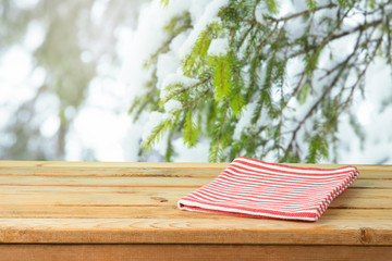 Empty wooden table with tablecloth over snow pine tree branches background