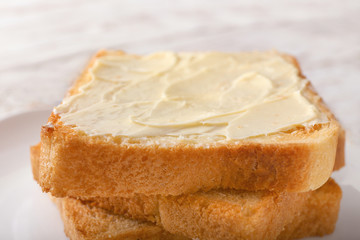 Tasty toasted bread with butter on plate, closeup