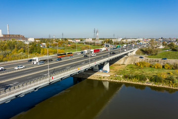 Fototapeta premium Aerial view of traffic jams on an automobile bridge with many vans and cars. Highway passes through the river and leads to the center of Warsaw, Poland. 