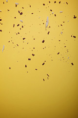 White and dark chocolate pieces and chipson on a bright yellow background. View from above. Flat lay.