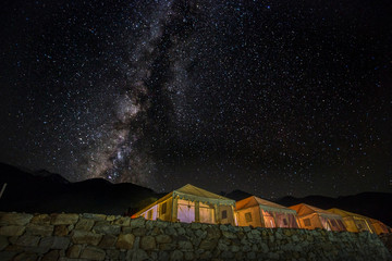 Milkyway galaxy  shining above illuminated tents near pangong lake, ladakh