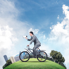 Businessman with megaphone in hand on bike
