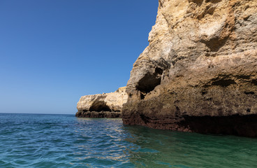 Beautiful landscape of Algarve, Portugal coast with sandstone cliffs, beach and ocean under cloudless blue sky	