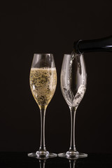 pour champagne in two glasses on a white or black background