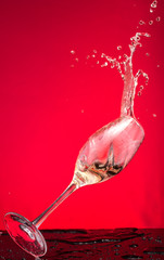 champagne is poured after a glass falls, splash and splatter on a red background
