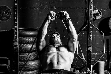 Young strong focused fit muscular man chest bench press stretching cross workout training in the gym with rubber for strength and good looking of muscles dark image real people selective focus