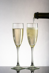 pour champagne in two glasses on a white or black background