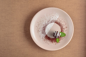 Chocolate ball with mint on a beige plate.