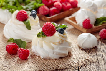 Dessert Pavlova with raspberries, blueberries and mint on a old wooden table.