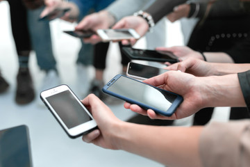 close up. young people with smartphones sitting in a circle