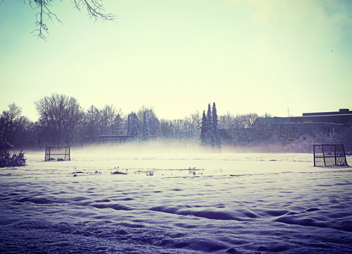 Winter in rural Bavaria, amatorial soccer field coverwev by snow and morning fog