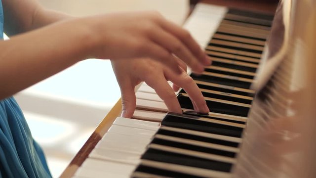 Young beautiful girl plays the piano. Hands close up. Music lessons.