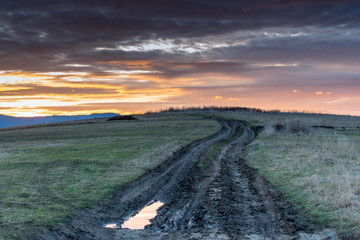 Dirt road leading to the top of the hill at sunset in the Carpathian mountains