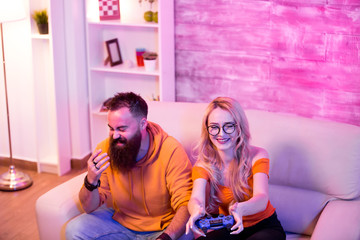 Happy young couple playing online video games on console