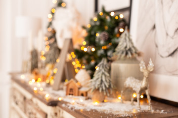 Fototapeta na wymiar Blurred closeup of wooden deer standing on background of Christmas decoration