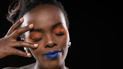 Beautiful close up shot of woman african face with colorful makeup blue and orange fashion, shooting studio shot isolated on black background.