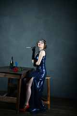 girl in a blue evening dress with a cigarette near the table