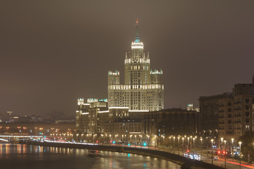 Fototapeta na wymiar Moscow cityscape at autumn night. Stalinist neoclassical style house on the Kotelnicheskaya embankment, Ship on the Moskva River. Long exposure photography