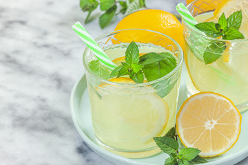 Lemon lemonade in mason jar glass ofwith lemons and straw on table background
