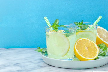 Lemon lemonade in mason jar glass ofwith lemons and straw on table background