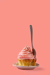 Homemade cupcake with pink buttercream and coconut flakes, with dessert fork within over red pink...