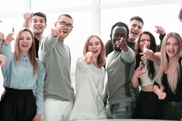 group of smiling young people pointing at one point