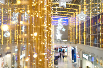 blurred photo people shopping during the fall and winter holiday season. christmas decoration of the shopping center. glowing lights garlands of gold color