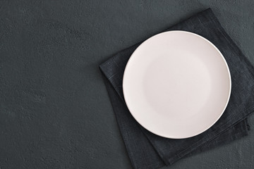 Empty plate on dark stone background.