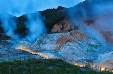Overview of Jigokudani or Hell Valley after sunset at Nobolibetus, Hokkaido Japan. The place is famous for dramatic crater with boiling sulfuric hot springs, volcanic steam plumes & hiking paths