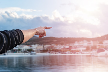 Man hand pointing to the right, outdoors at the pier during sunset.