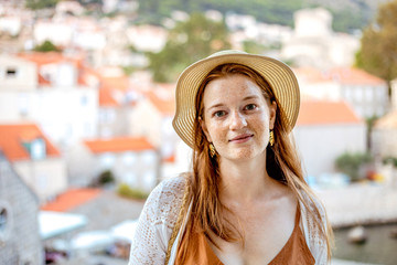 Young smiling woman in summer dress and hat on vacation in a Mediterranean resort in the old town. Discovering unknown corners of the world