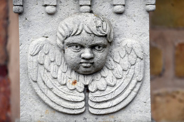 A sandstone sculpture of an angry looking angel with spread wings.